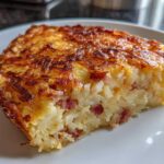 A close-up slice of baked hash brown quiche with a crispy, golden-brown top and visible bacon pieces inside.
