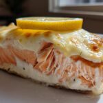 A thick slice of perfectly cooked Boursin Salmon topped with melted, slightly browned cheese and a lemon slice.