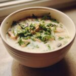 A close-up of a creamy bowl of Irresistible Thai Chicken Soup topped generously with fresh cilantro.