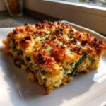 A square serving of Cheesy Lentil Bake Comfort Food with a golden, crispy, cheesy topping, served on a white plate.