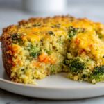 A serving of Cheesy Veggie Quinoa Casserole showing quinoa, broccoli, carrots, and a melted cheddar cheese topping.