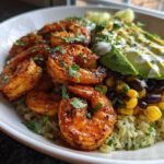 A vibrant Chipotle Lime Shrimp Bowl featuring seasoned shrimp, cilantro-lime rice, black beans, corn, and sliced avocado with crema.
