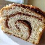 Close-up of a soft slice of Cinnamon Swirl Bread showing the beautiful brown cinnamon swirl pattern inside the white bread.