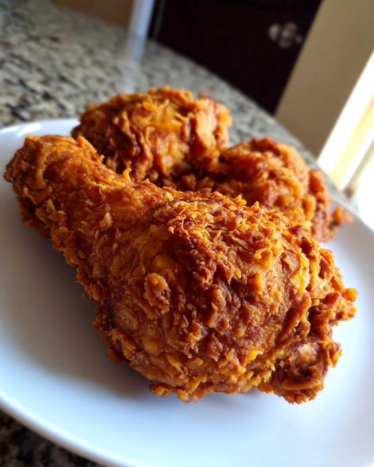 Close-up of a perfectly fried, crispy drumstick piece of Copycat Country Chicken on a white plate.