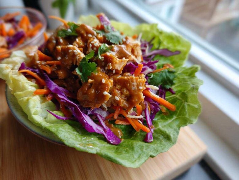 A single serving of Crunchy Thai Chicken Wraps featuring saucy chicken, shredded carrots, and purple cabbage in a crisp lettuce cup.