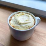 A close-up of the Decadent Cheesecake Mug Recipe, showing creamy filling and graham cracker crust in a white mug.
