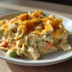 A close-up serving of creamy Dump and Bake Chicken Casserole topped with melted cheddar cheese and parsley.