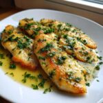 Four golden-brown fillets of Easy Flounder Francaise recipe served in a bright lemon-butter sauce and topped with fresh chopped parsley.