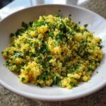 Close-up of bright yellow Easy Lemon Herb Quinoa topped generously with fresh chopped parsley in a white bowl.
