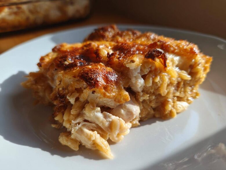 Close-up of a serving of French Onion Chicken Orzo Casserole with a golden-brown, cheesy top.