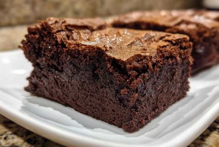 Close-up of a rich, dark, fudgy brownie slice showing its dense interior and shiny top crust.