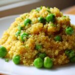 A mound of golden Garlic Butter Quinoa Green Peas garnished with fresh parsley on a white plate.