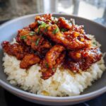 Close-up of a bowl of Hawaiian Chicken Coconut Rice, featuring sticky, glazed chicken over white coconut rice.