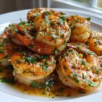 A close-up of succulent Hawaiian Garlic Shrimp coated in a rich, buttery garlic sauce and fresh parsley.