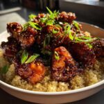 Close-up of glazed Honey Garlic Chicken Quinoa bowl topped with sesame seeds and fresh scallions.
