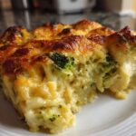 A close-up of a cheesy slice of Keto Broccoli Cauliflower Au Gratin showing melted, browned cheese and tender vegetables.