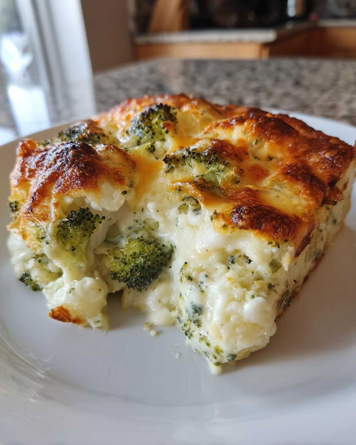 A close-up of a cheesy slice of Keto Broccoli Cauliflower Au Gratin with a browned top.