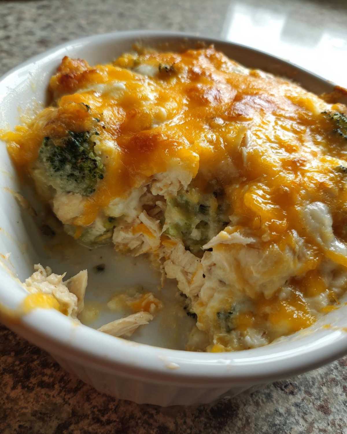 Close-up of a scoop taken out of a Low Carb Chicken Casserole topped with melted cheddar and mozzarella.