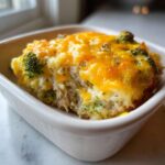 A close-up of a single serving of Low Carb Chicken Casserole topped with melted cheddar cheese and broccoli florets.
