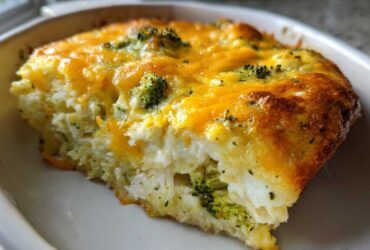 A close-up slice of Low Carb Chicken Casserole featuring shredded chicken, broccoli, and a golden melted cheddar cheese topping.