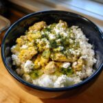 Close-up of a Low Carb Lemon Dill Chicken Bowl featuring cauliflower rice, chicken pieces, feta cheese, and fresh dill.