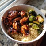 Close-up of a Maple Dijon Chicken Bowl featuring glazed chicken pieces, roasted Brussels sprouts, and a base of fluffy quinoa.