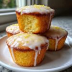A stack of four glazed Mini Lemon Cakes Recipe, showing the moist interior of one cake.