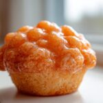 Close-up of a golden muffin generously topped with a thick, shiny Fluffy Orange Muffin Glaze.