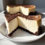 Two slices of creamy Nobake Cheesecake Silky Sets Perfectly on a white plate, showing a thick chocolate crust and topping.