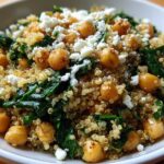 A close-up of the finished One Pot Chickpea Quinoa Recipe, topped with feta cheese and wilted spinach.