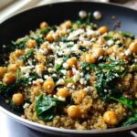 Close-up of a One Pot Chickpea Quinoa Recipe with wilted spinach and crumbled feta cheese in a black skillet.