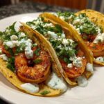 Three delicious Shrimp Tacos with Lime Crema, topped with crumbled white cheese and fresh cilantro.