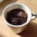 Close-up of a rich, dark chocolate Single Serve Protein Brownie baked inside a white mug.
