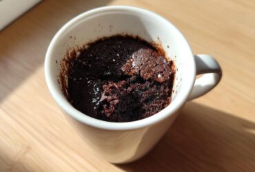 Close-up of a rich, dark chocolate Single Serve Protein Brownie baked inside a white mug.