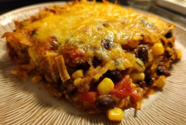 Close-up of a cheesy slice of Southwestern Black Bean Casserole showing black beans, corn, and melted cheese.