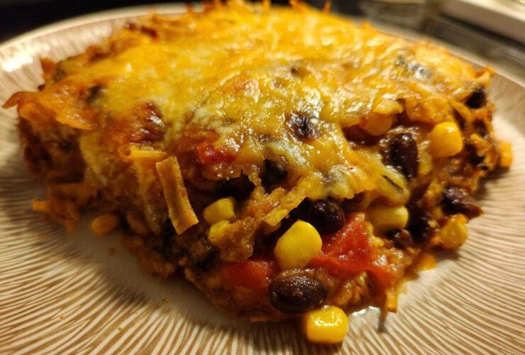 Close-up of a cheesy slice of Southwestern Black Bean Casserole showing black beans, corn, and melted cheese.