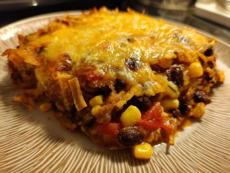 Close-up of a cheesy slice of Southwestern Black Bean Casserole showing black beans, corn, and melted cheese.