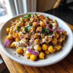 Close-up of a bowl of Spicy Chickpea Salad topped with creamy sauce, red onion, and spices.
