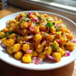 Close-up of a vibrant Spicy Chickpea Salad tossed with red onion and cilantro on a white plate.