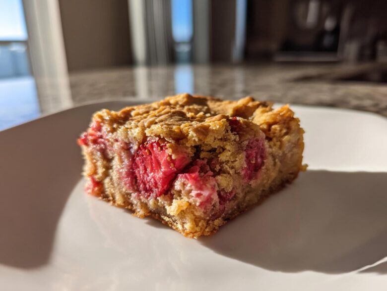 A single square of moist Strawberry Blondies One Bowl recipe featuring visible chunks of bright red strawberries.