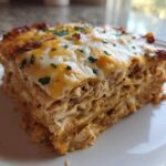 A close-up slice of rich, layered Texas King Ranch Chicken Casserole topped with melted cheese and parsley.