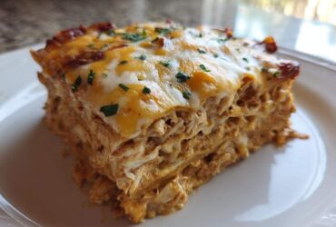 A close-up slice of rich, layered Texas King Ranch Chicken Casserole topped with melted cheese and parsley.
