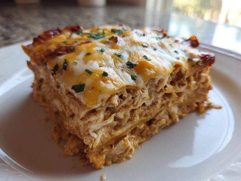 A close-up slice of rich, layered Texas King Ranch Chicken Casserole topped with melted cheese and parsley.