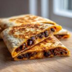 Close-up of two stacked slices of crispy Vegan Black Bean Quesadillas showing melted vegan cheese and black bean filling.