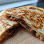 Two golden brown slices of Vegan Black Bean Quesadillas, showing the melted filling and crispy tortilla.