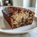 Close-up of a moist slice of Banana Bread Chocolate Chip loaf showing rich chocolate chips throughout the crumb.