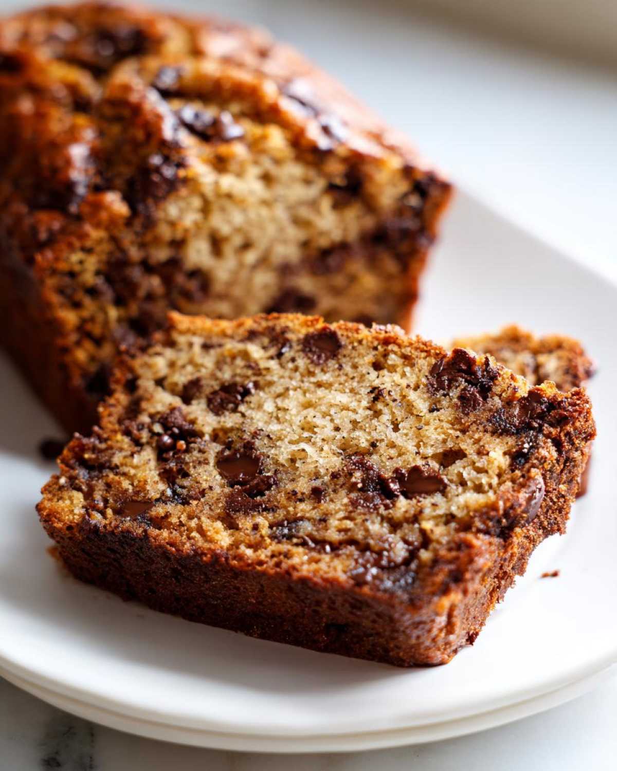 Close-up of a thick slice of moist Banana Bread Chocolate Chip showing melted chocolate chips throughout the crumb.