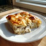 A serving of creamy Chicken Crescent Roll Casserole with a golden, flaky crust on a white plate.