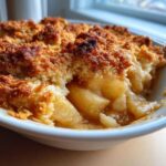 A close-up view of a serving of homemade Apple Crisp showing tender, spiced apples beneath a crunchy, golden-brown topping.