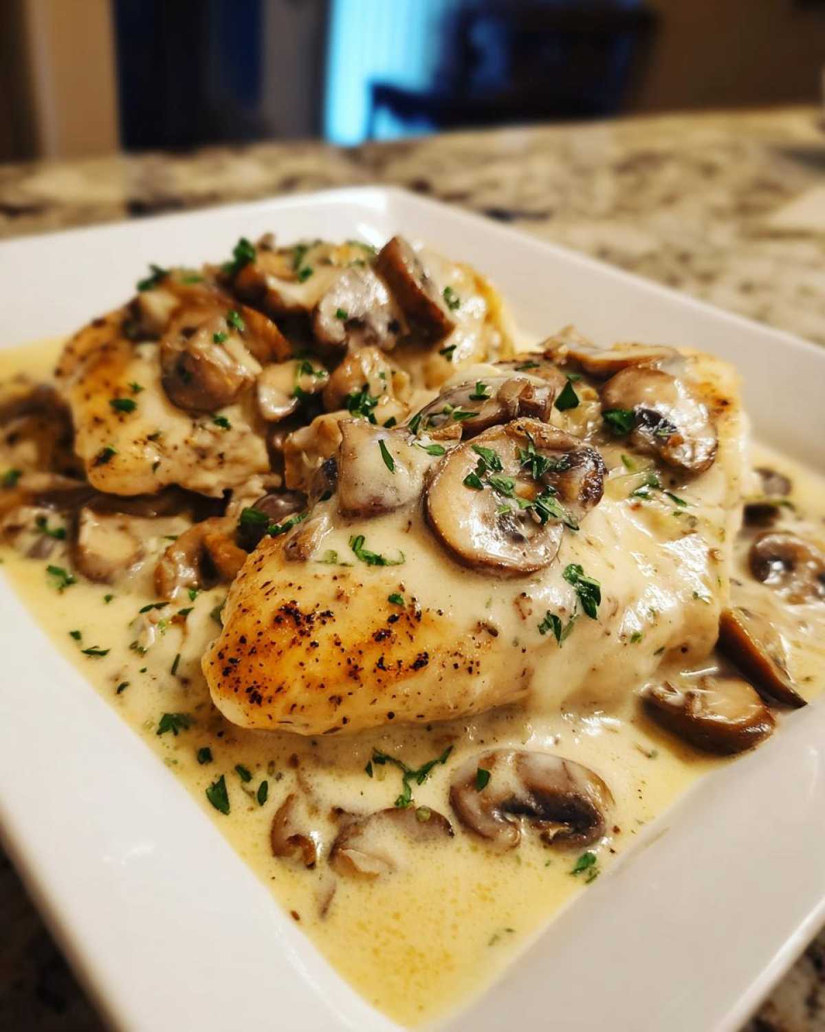 Two golden-brown chicken breasts covered in a rich, creamy mushroom sauce, ready to serve as Creamy Smothered Chicken.